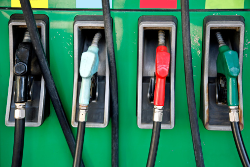 Multi colored gas pumps on green background.