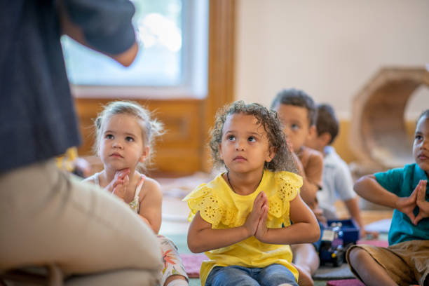 Preschool kids doing yoga Group of diverse children in the classroom stretching and doing yoga and listening to the teacher. mindfulness children stock pictures, royalty-free photos & images