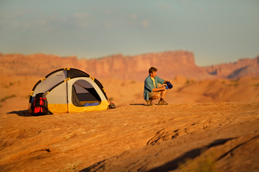 Man pouring Coffee beside Tent and backpack near Moab, Utah