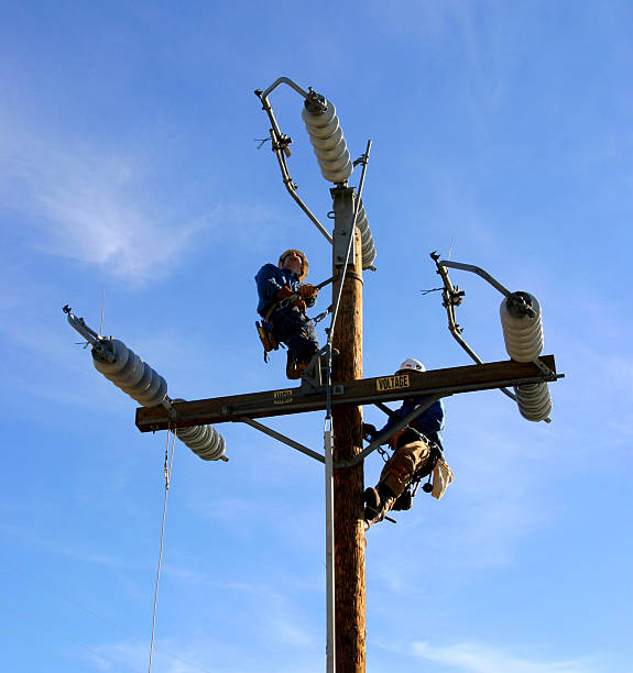 Electrical linemen on electric power pole stock photo