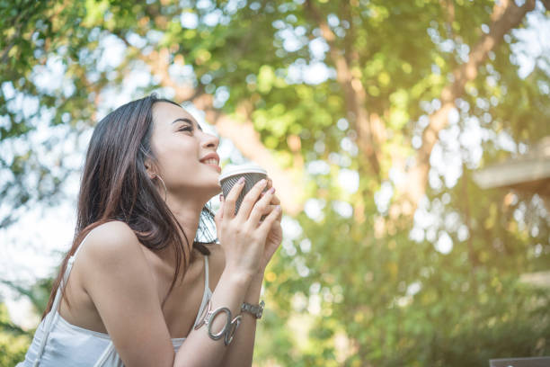 sentimento bonito novo da mulher feliz e poderoso ao beber o café no parque na manhã - fresh coffee audio - fotografias e filmes do acervo