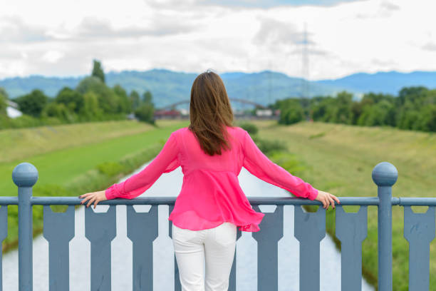 istock Young woman standing looking out over a river 1159326767