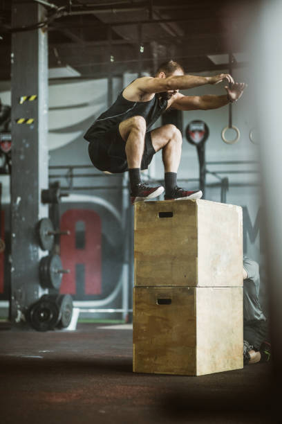 istock Athletic man jumping on a crate while having sports training in a gym. 1159328915