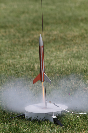 A model rocket lifts off from the launching pad.