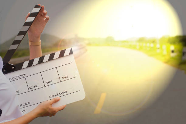 istock Girl holding a clapboard on road background. 1159331446