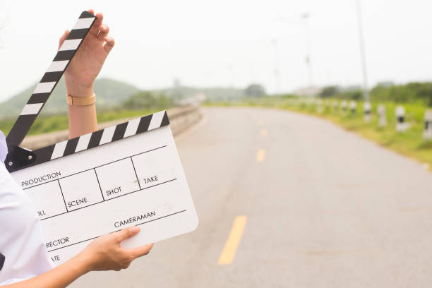 istock Girl holding a clapboard on road background. 1159331508