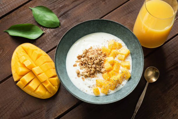 istock Natural yogurt with mango slices and crunchy granola in bowl 1159331555