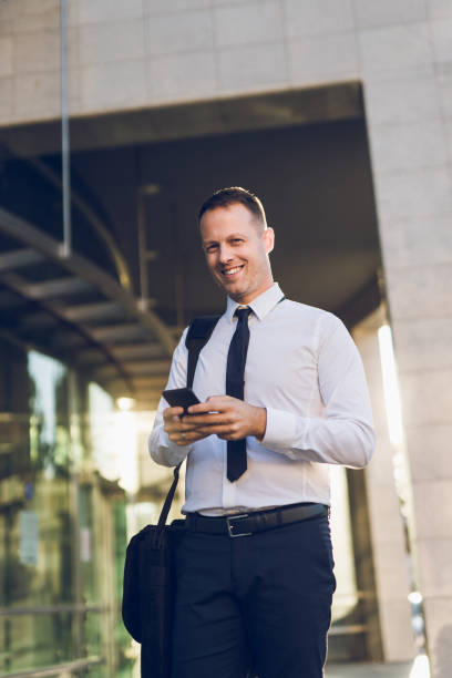 istock Businessman reading text message on mobile phone outdoors 1159333464