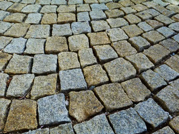 textured rough and rustic cube quartz stone pavement abstract of square shapes loosely set in crushed limestone base in circular fashion. street and walkway paving design concept.