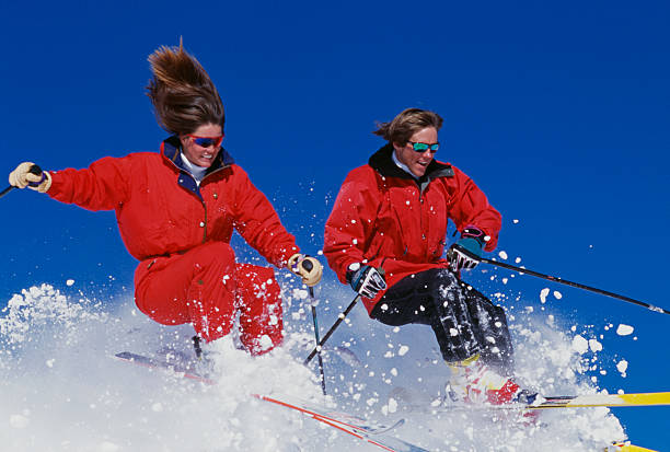 Couple Snow Skiing Man and Woman Snow Skiing and Jumping  Against Blue Sky skiing photos stock pictures, royalty-free photos & images