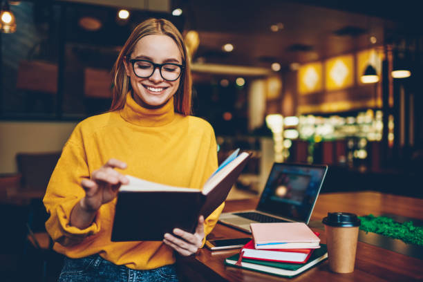 istock Charming emotional talented female student dressed in casual clothes sincerely laughing while spending time in coffee shop.Beautiful successful hipster girl reading information from notepad indoors 1159341320