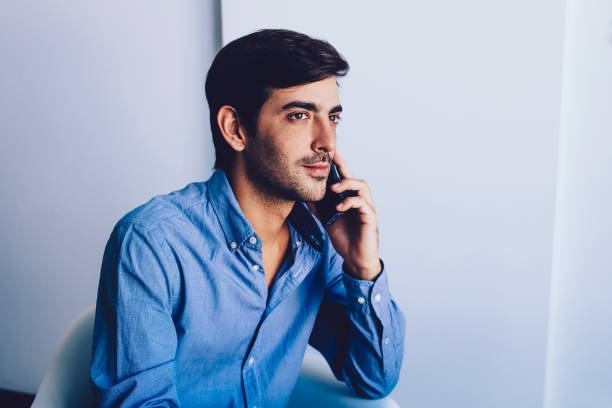 istock Handsome good looking male manager calling to customer service via mobile phone after work in office, indian concentrated man thoughtful looking away during telephone conversation and consultancy 1159342321