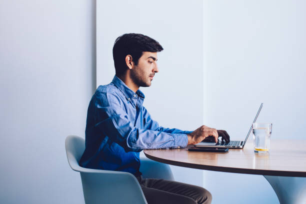 istock Serious indian male it professional typing program code at laptop device sitting at office table, young businessman browsing wireless internet updating software application on modern netbook 1159342324