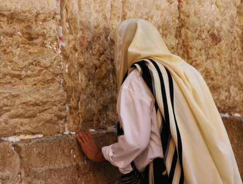 Jewish man praying at the wailing wall in jerusalem. notes ,scattered in the wall cranks, are messages to god, an old time jewish tradition.