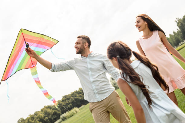 istock Feeling happy! Active parents and child daughter launcing a kite in the field. 1159344592