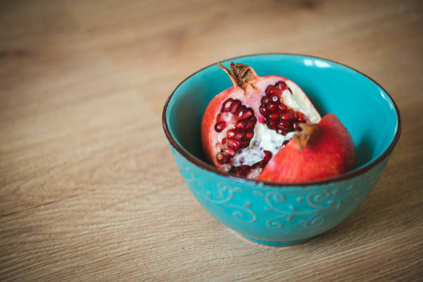 Pomegranate fruit in two halves in a blue bowl.