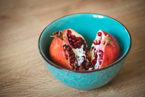 istock Pomegranate fruit in two halves in a blue bowl. 1159346239