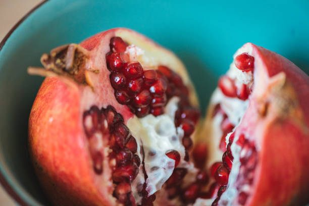 istock Pomegranate fruit in two halves in a blue bowl. 1159346240