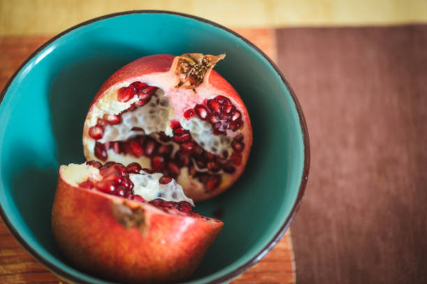 istock Pomegranate fruit in two halves in a blue bowl. 1159346312