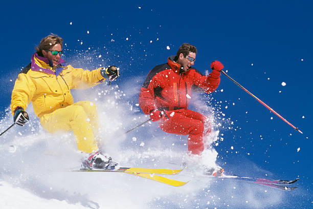 deux skieurs de neige saut contre le ciel bleu - champ de bosses photos et images de collection