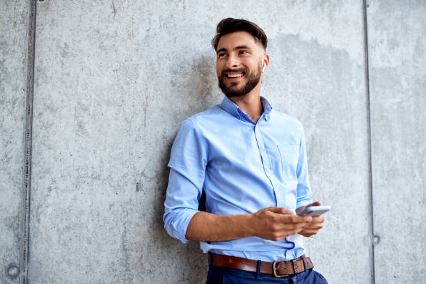 Smiling young businessman looking away while talking on phone with wireless headphones