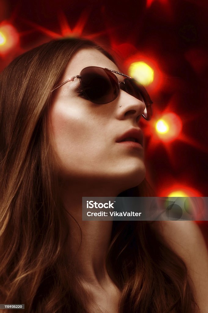 dsco female in sunglasses with coulorful lights on background Adult Stock Photo