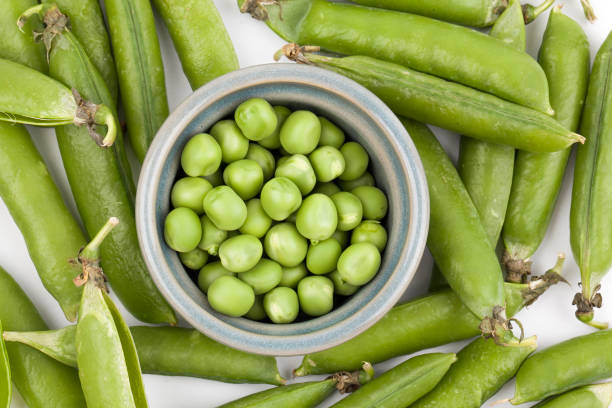 istock fresh pea pods isolated on white background. 1159355862