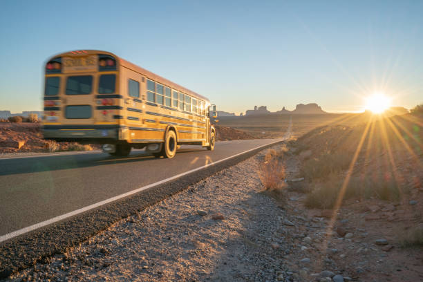 autobus scolaire sur l'autoroute au coucher du soleil dans la nature - navajo national monument photos et images de collection