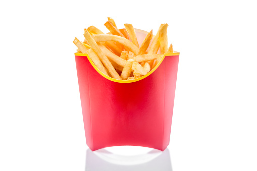French fries potatoes in red fry box isolated on white background with reflection.