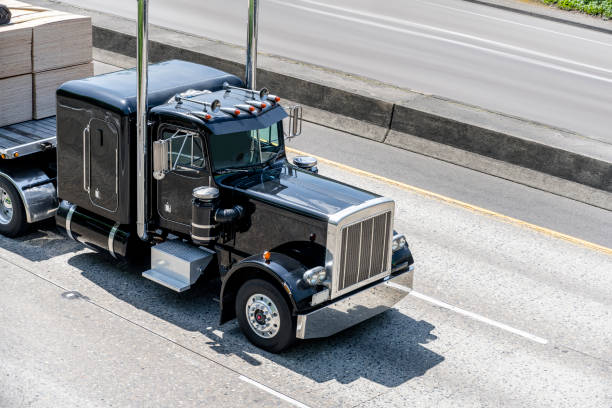 istock Black powerful big rig classic semi truck transporting cargo on flat bed semi trailer moving on multiline highway 1159357597