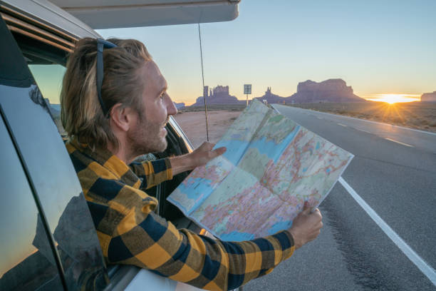 istock Road trip concept; Young man inside campervam looking at road map for directions exploring national parks and nature ready for adventure. 1159357892