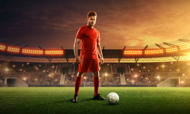istock Soccer player with a ball on a floodlit stadium. 1159360354