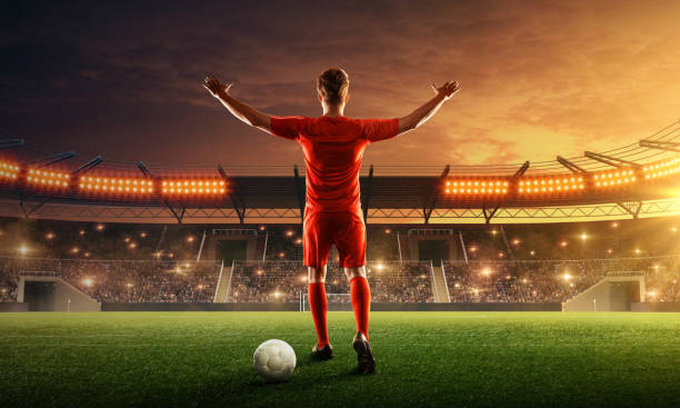 istock Soccer player celebrates victory on a floodlit night stadium 1159360423