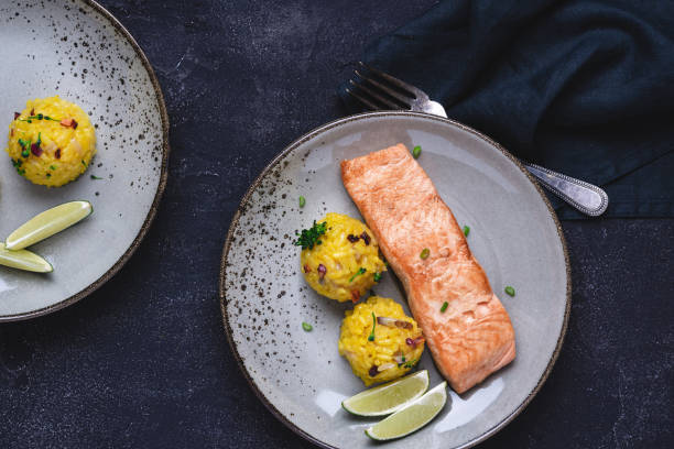 istock Grilled Salmon Steak with Yellow Risotto and Lime on Stone Background 1159362024
