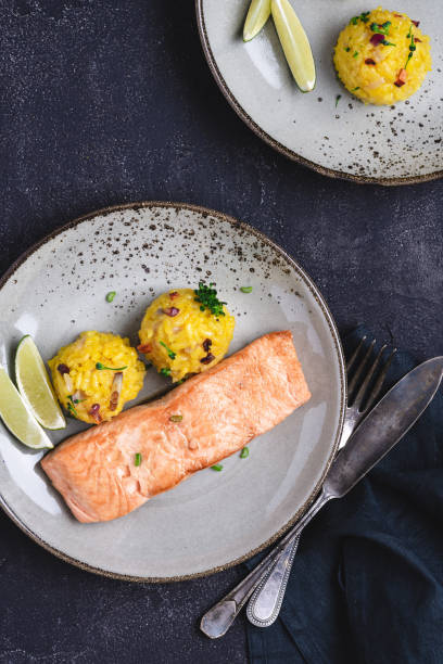 istock Grilled Salmon Steak with Yellow Risotto and Lime on Stone Background 1159362026