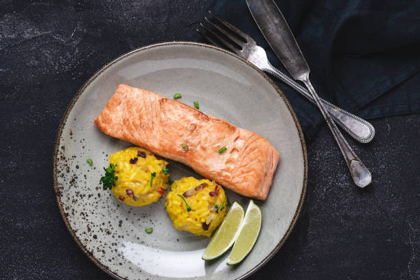 istock Grilled Salmon Steak with Yellow Risotto and Lime on Stone Background 1159362028