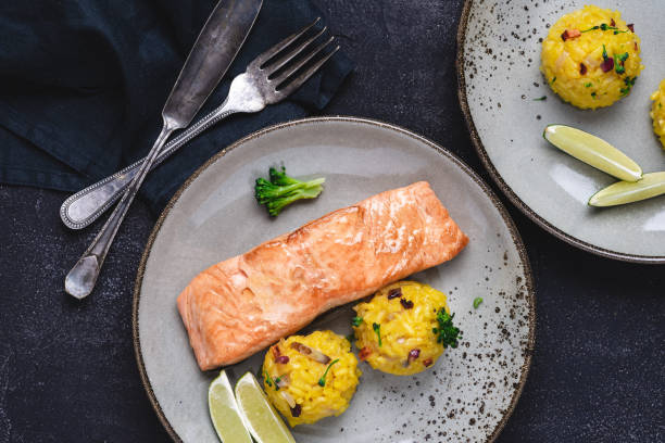 istock Grilled Salmon Steak with Yellow Risotto and Lime on Stone Background 1159362030