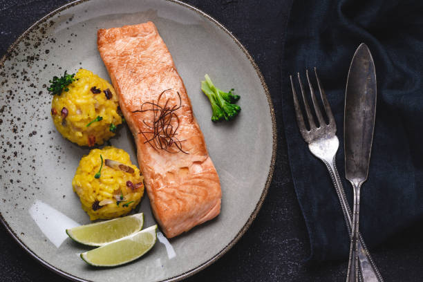 Grilled Salmon Steak with Yellow Risotto and Lime on Stone Background