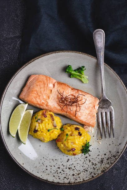 istock Grilled Salmon Steak with Yellow Risotto and Lime on Stone Background 1159362036