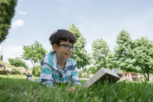 istock Happy boy reading book on the grass 1159363849