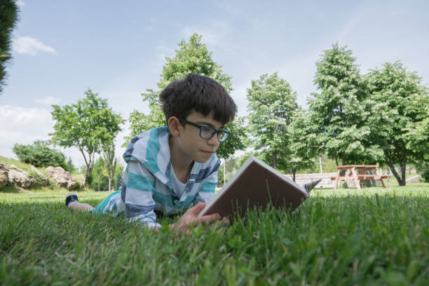 istock Happy boy reading book on the grass 1159363914