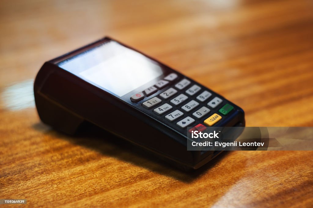 Payment terminal lying on a wooden table Airport Terminal Stock Photo