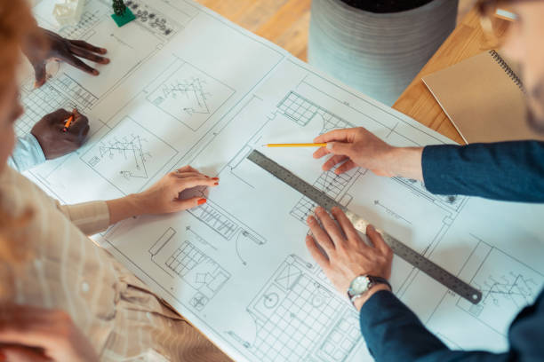 Men and woman using ruler and pencil while drawing sketches