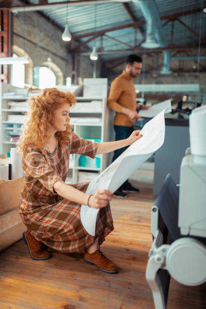istock Stylish interior designer looking at the printed sketches 1159365616