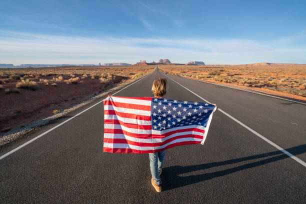 istock Man on road holding American flag 1159366361