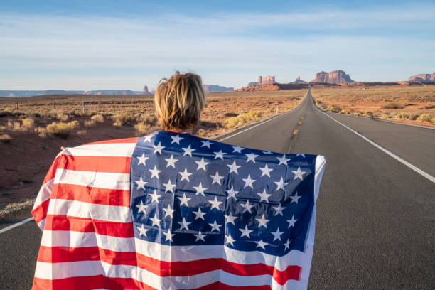 istock Man on road holding American flag 1159366669