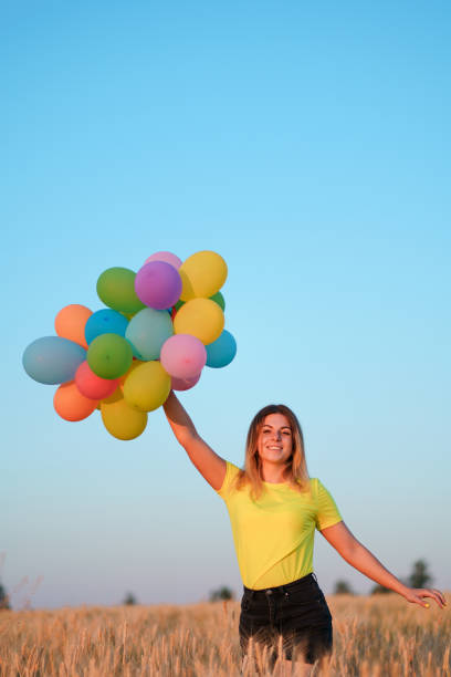 istock happy woman with multicolored balloons at sunset 1159367234