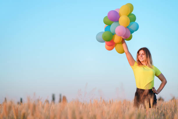 istock happy woman with multicolored balloons at sunset 1159367239