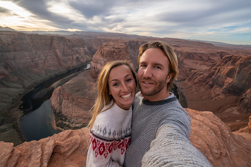 Couple traveling in USA take selfie picture at the horseshoe bend; people adventure travel concept