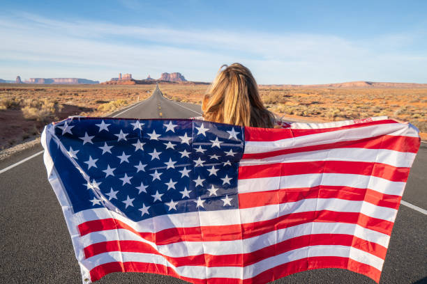 istock Girl on road holding American flag 1159367408